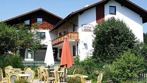 A two-story building with a balcony and outdoor seating area. - Ferienwohnungen Wirth (Bodenmais)