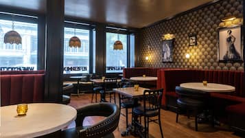 Un interior de restaurante con cabinas, mesas redondas y lámparas colgantes.