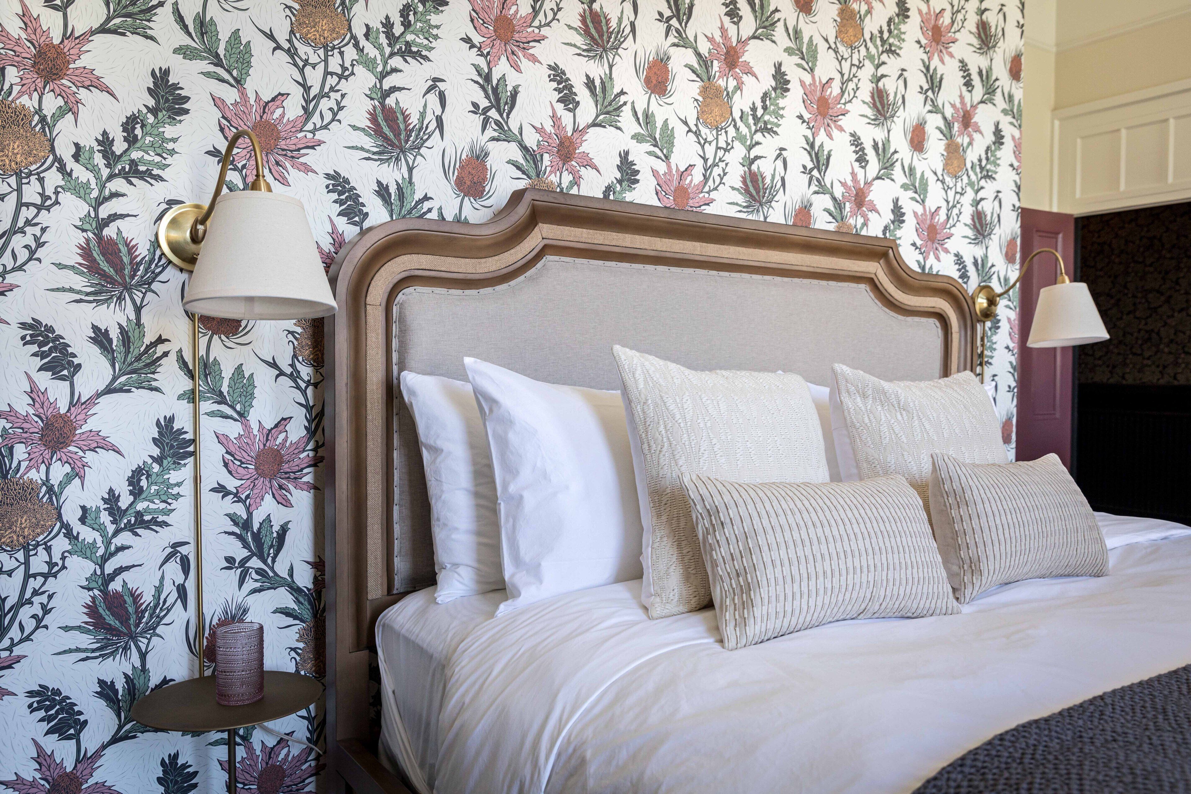 A neatly made bed with a wooden headboard, white bedding, and a decorative pillow.