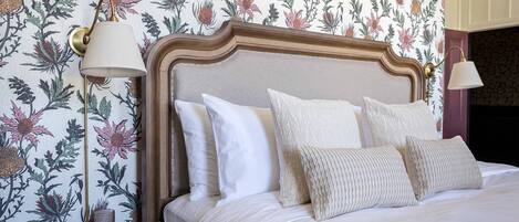 A neatly made bed with a wooden headboard, white bedding, and a decorative pillow.