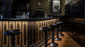 Een bar met behang met een patroon, barstoelen en een ingelijste foto aan de muur.