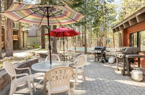 Enjoy al fresco dining on the patio, surrounded by trees and a fence, with a barbecue grill and comfortable seating for six.