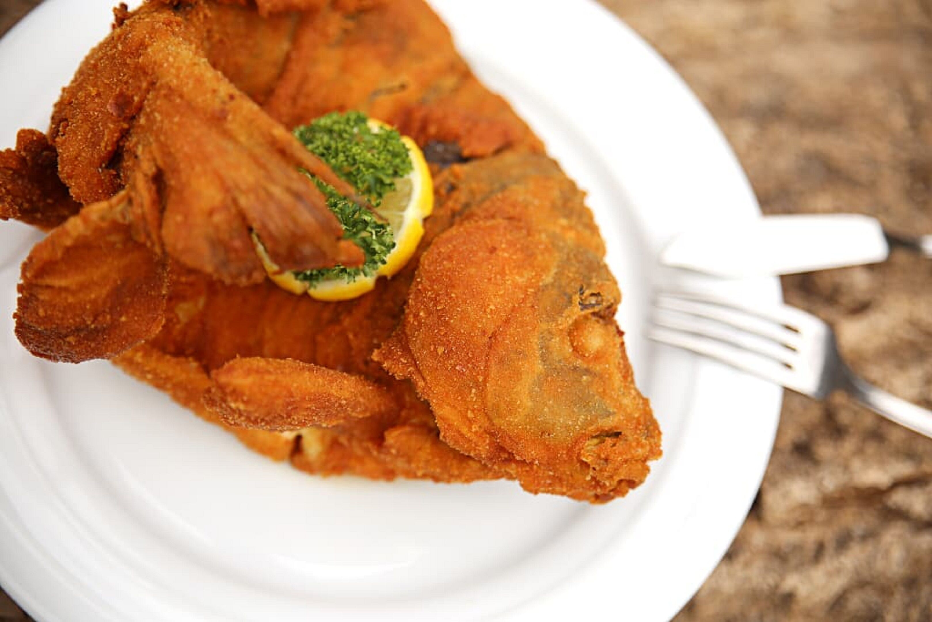 Une assiette de poisson frit, garnie de persil et de citron.