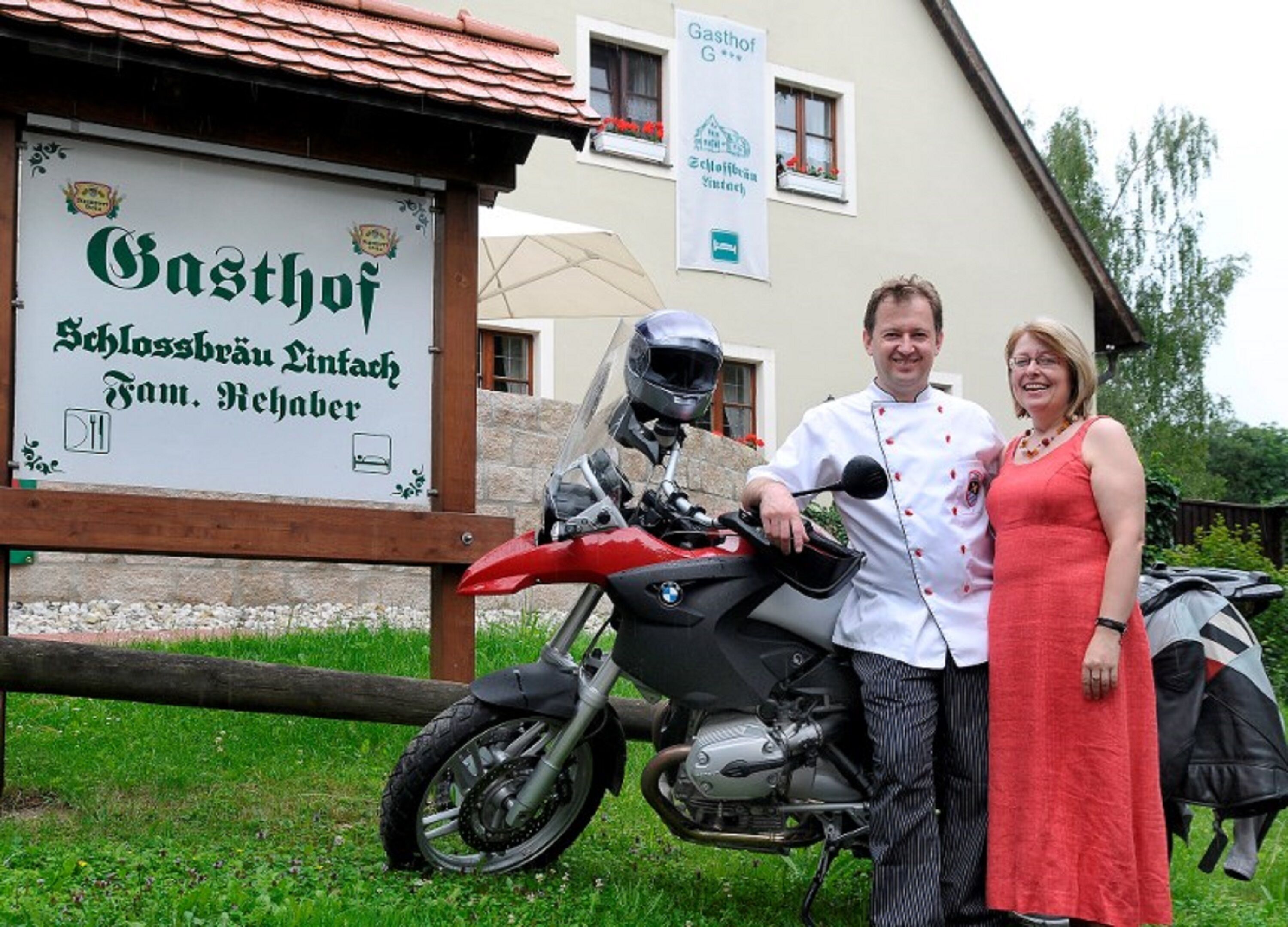 A motorcycle parked in front of a building with a sign that reads "Gasthof Schlossbräu Linz".