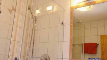 A bathroom with a glass-enclosed shower, a white sink, and a mirror with a wooden frame.