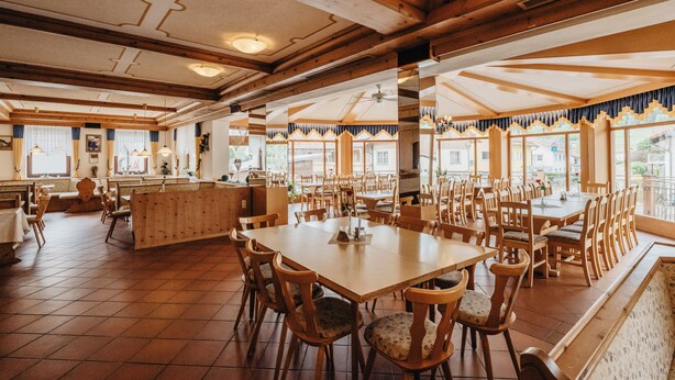A restaurant with wooden furniture, large windows, and a high ceiling. - Gasthof-Metzgerei-Pension Schierlitz (Rimbach)