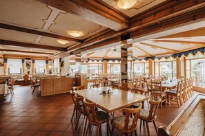 Un restaurant doté de meubles en bois, de grandes fenêtres et d’un plafond haut.
