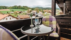 A table with a bottle and glasses, a chair, and a view of a village. - Gasthof-Metzgerei-Pension Schierlitz (Rimbach)