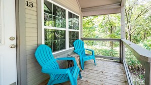 Une véranda avec deux fauteuils Adirondack turquoise et une table en bois.