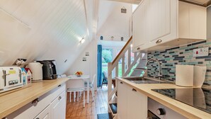 Una cocina compacta con armarios blancos, una encimera de madera y un salpicadero de azulejos.