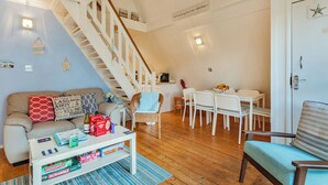 Una sala de estar acogedora con un sofá, una mesa de centro y una zona comedor con sillas y una mesa.