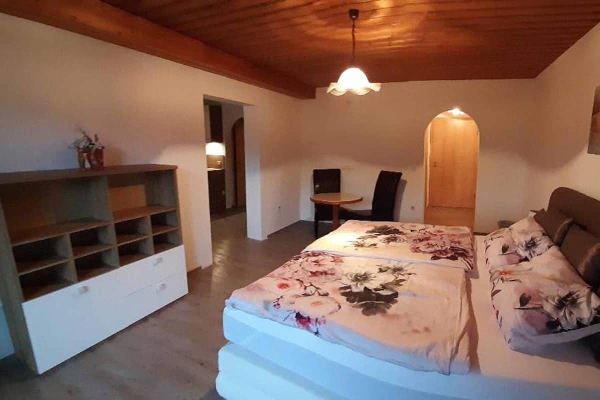 A bedroom with a bed, a desk, a chair, and a shelving unit.