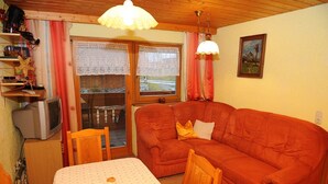 A cozy living room with a sofa, a table, and a television. - Woferlhof Ferienhof Boxhorn (Böbrach)