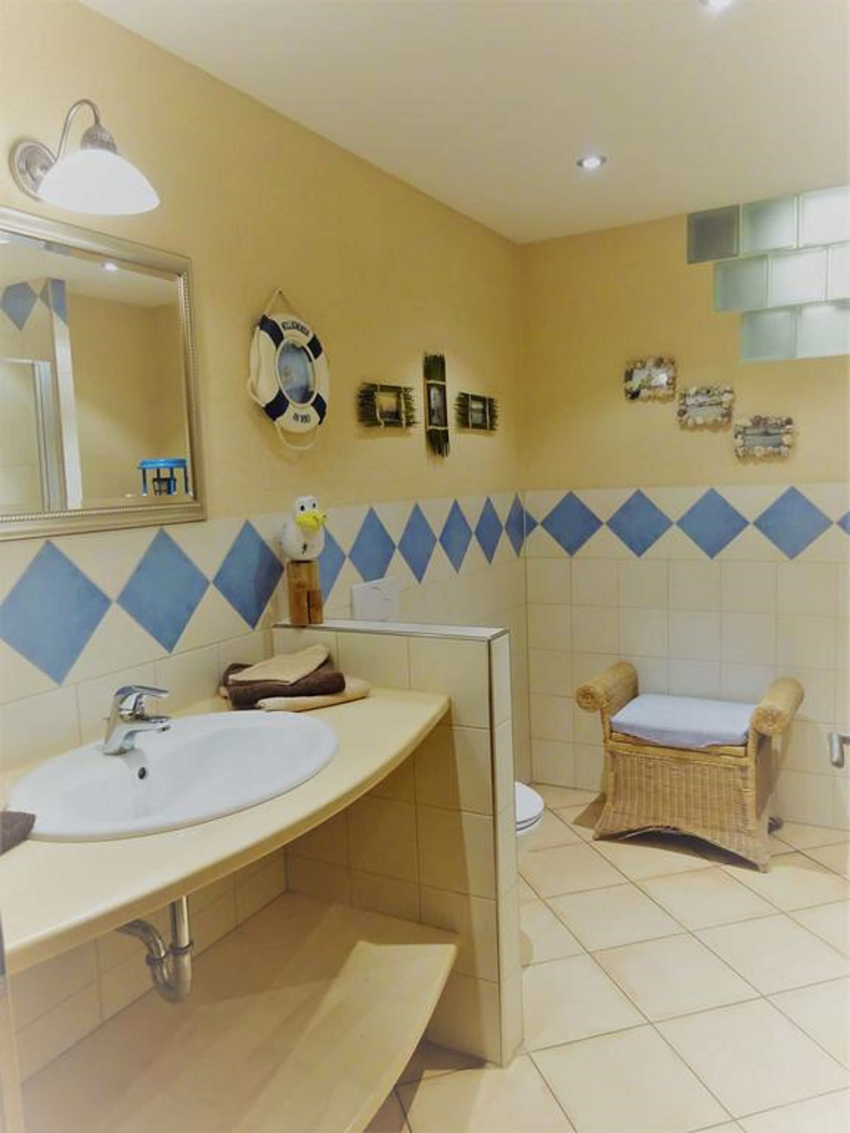 A bathroom with a sink, mirror, and a small wicker chair.