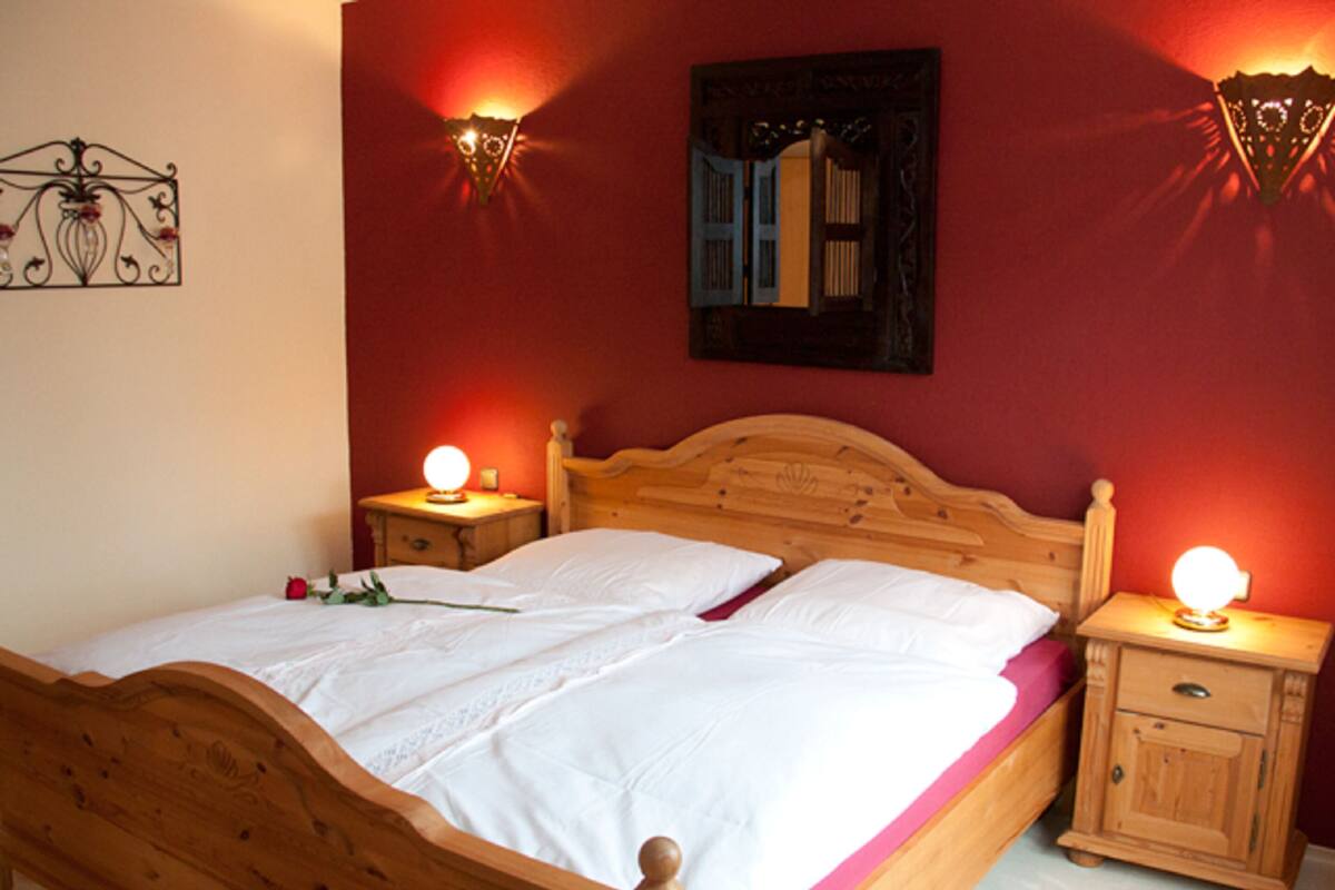 A wooden bed with white bedding and two bedside tables with lamps.