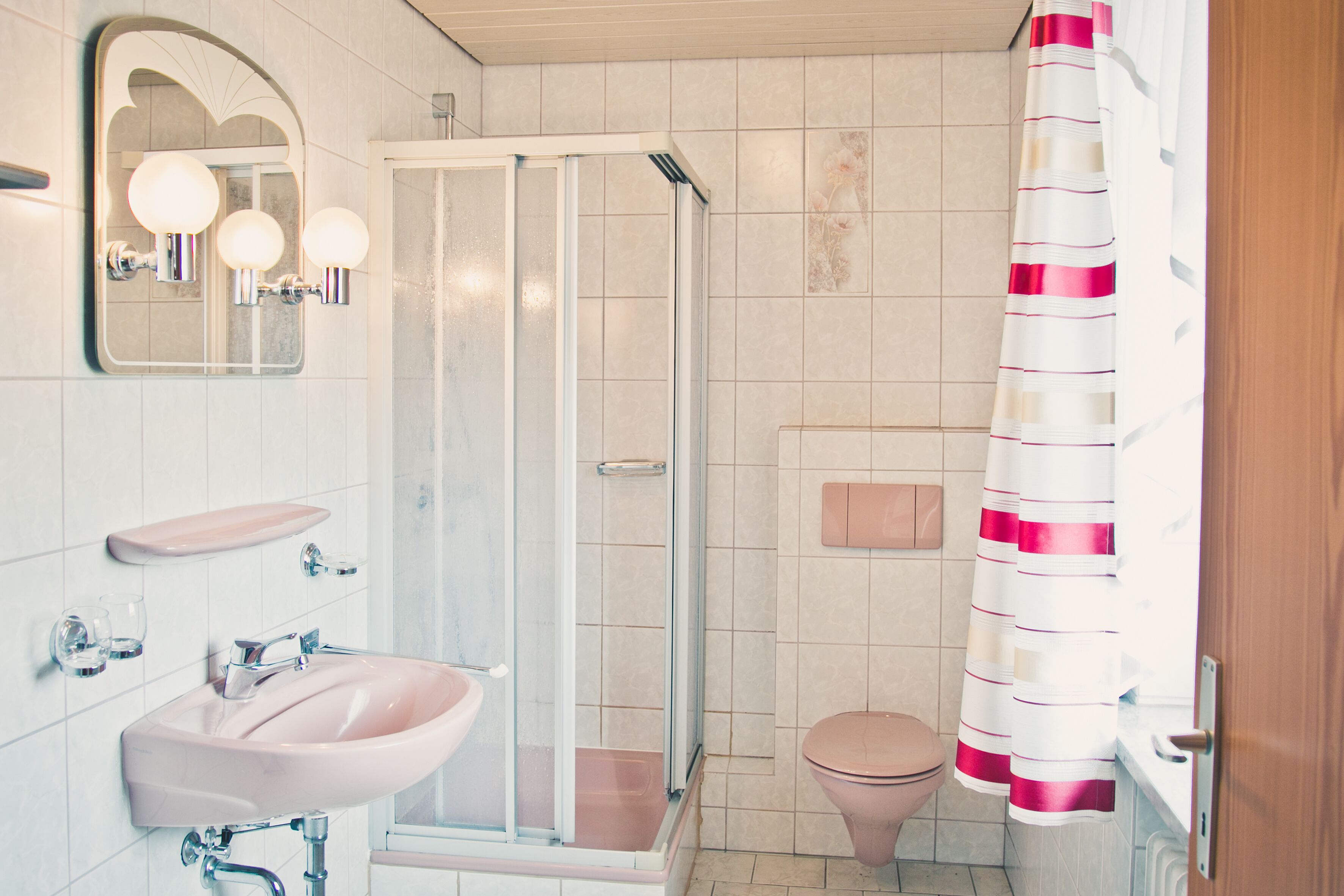 Une salle de bain avec une douche à parois de verre, un lavabo, des toilettes et un miroir avec éclairage intégré.