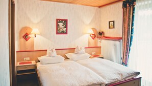A hotel room with two beds, a wooden ceiling, a radiator, and two wall-mounted lamps. - Stan's Bed & Breakfast (Untergriesbach)