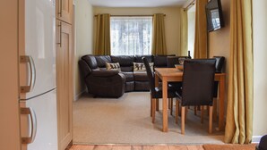 A compact living space with a kitchenette, a sofa set, a dining table with chairs, and a flat-screen TV mounted on the wall. - 2 bedroom accommodation in Topsham, near Exeter (Topsham, near Exeter)
