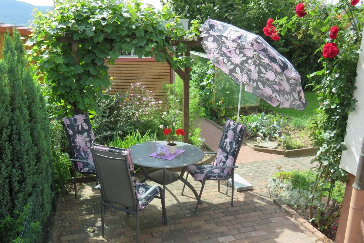 A patio with a round table, two chairs, and a floral umbrella.
