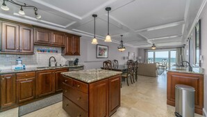 Una cocina amplia con gabinetes de madera, encimeras de granito e iluminación colgante.