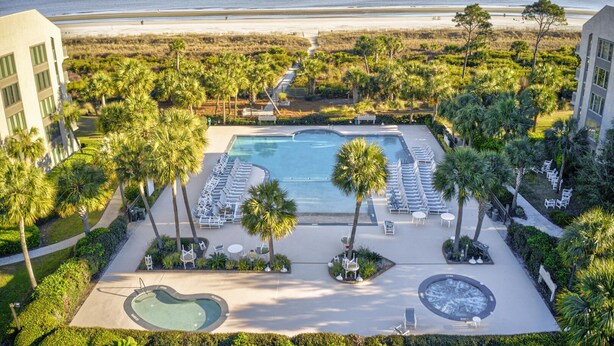 Un resort con piscina, sillones de descanso y palmeras.