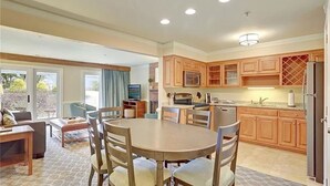 A spacious kitchen with wooden cabinets, a dining area with a round table and chairs, and a view through the glass doors. - Water-view in Kingsmill, 10 minutes to Busch Gardens & Colonial Williamsburg! (Williamsburg)