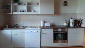 A modern kitchen with white cabinetry, a Bosch dishwasher, a Bosch stove, a coffee maker, and a toaster. - Ferienwohnung Lucretia a3 (Ruhstorf)