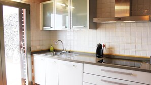 A modern kitchen with white cabinets, a stainless steel sink, and a built-in oven. - The best views of the island of Tenerife (Juan Fernández)