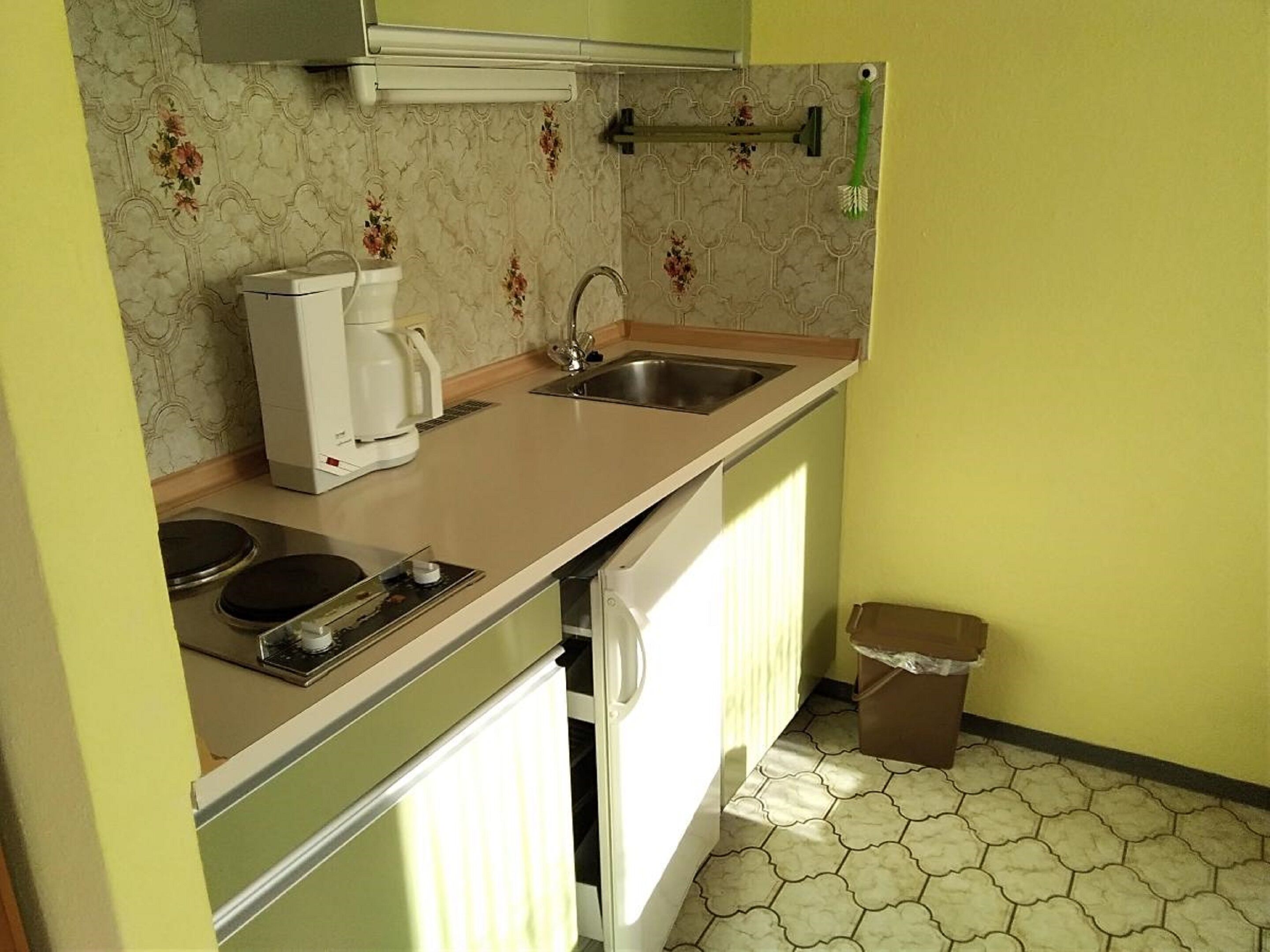 A compact kitchen with a sink, a coffee maker, and a stove.