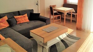 Un salon comprenant un canapé, une table basse, une table à manger avec des chaises et un tableau accroché au mur.