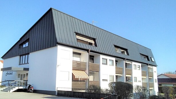 Un bâtiment moderne à deux étages, doté d’un toit en pente, de nombreuses fenêtres et d’une entrée bien visible avec des marches.