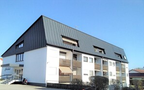 Un bâtiment moderne à deux étages, doté d’un toit en pente, de nombreuses fenêtres et d’une entrée bien visible avec des marches.