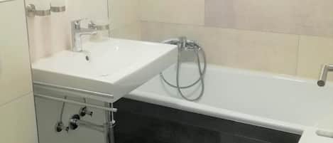A modern bathroom with a white sink, a bathtub, and a toilet.