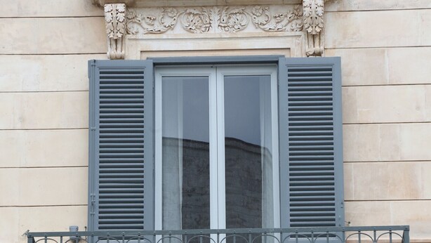Eine Gebäudefassade mit einem Fenster und einem Balkon mit schmiedeeisernen Geländern.