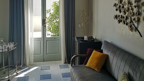 Una sala de estar con un sofá, una mesita con vasos, un adorno en la pared y vistas a través de una puerta.