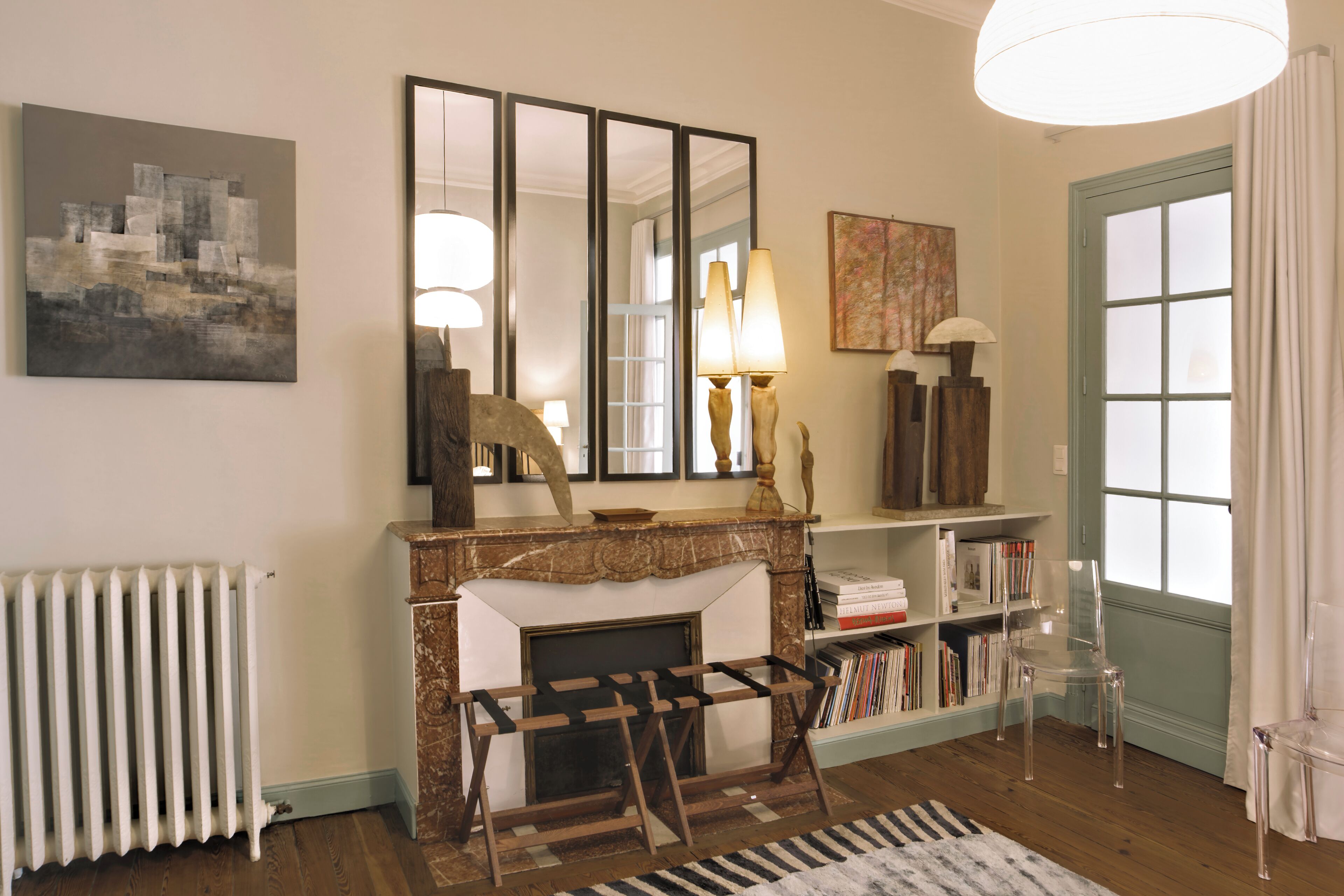 Un salon avec une cheminée, des étagères à livres, un miroir et un radiateur.