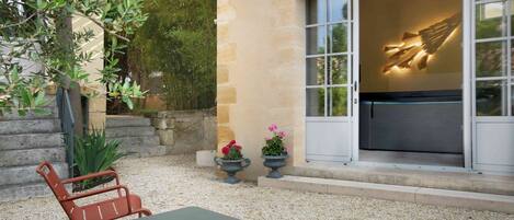 A patio with a table and chairs, a stone wall, and a sliding glass door with a decorative light fixture.