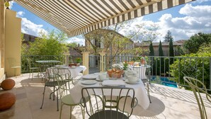 An outdoor dining area with tables and chairs, a pool in the background, and a covered patio. - Clos d'Argenson (Bergerac)