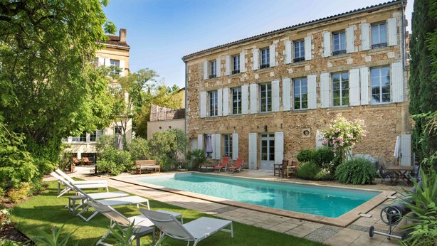 A poolside area with lounge chairs, a swimming pool, and a stone building with shutters. - Clos d'Argenson (Bergerac)