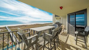 A balcony with a table and chairs overlooking a beach. - Phoenix VII 7508 | Luxury Gulf-Front Condo (Orange Beach)