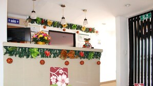 Ein Hotelrezeptionstresen mit einer Weihnachtsgirlande, einem Fernseher und einem Schild für die Toilette.