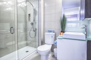 Een moderne badkamer met een douchecabine van glas, een wit toilet en een wastafel met glazen blad.