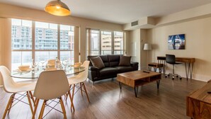 Ein modernes Wohnzimmer mit einem Glastisch, einem schwarzen Sofa und einem Couchtisch aus Holz.