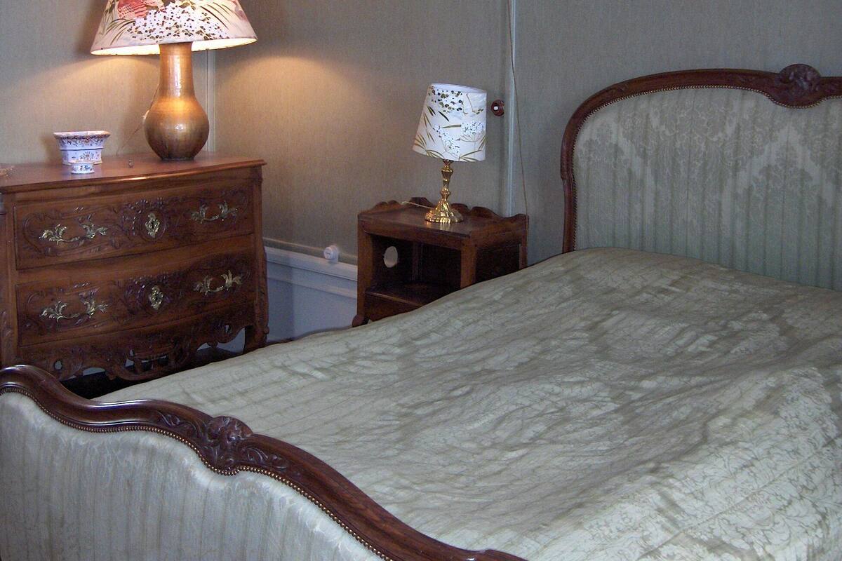 A bedroom with a bed, two nightstands, a lamp, and wall art.