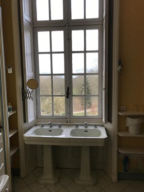 Un baño con dos lavamanos, una ventana y un espejo.