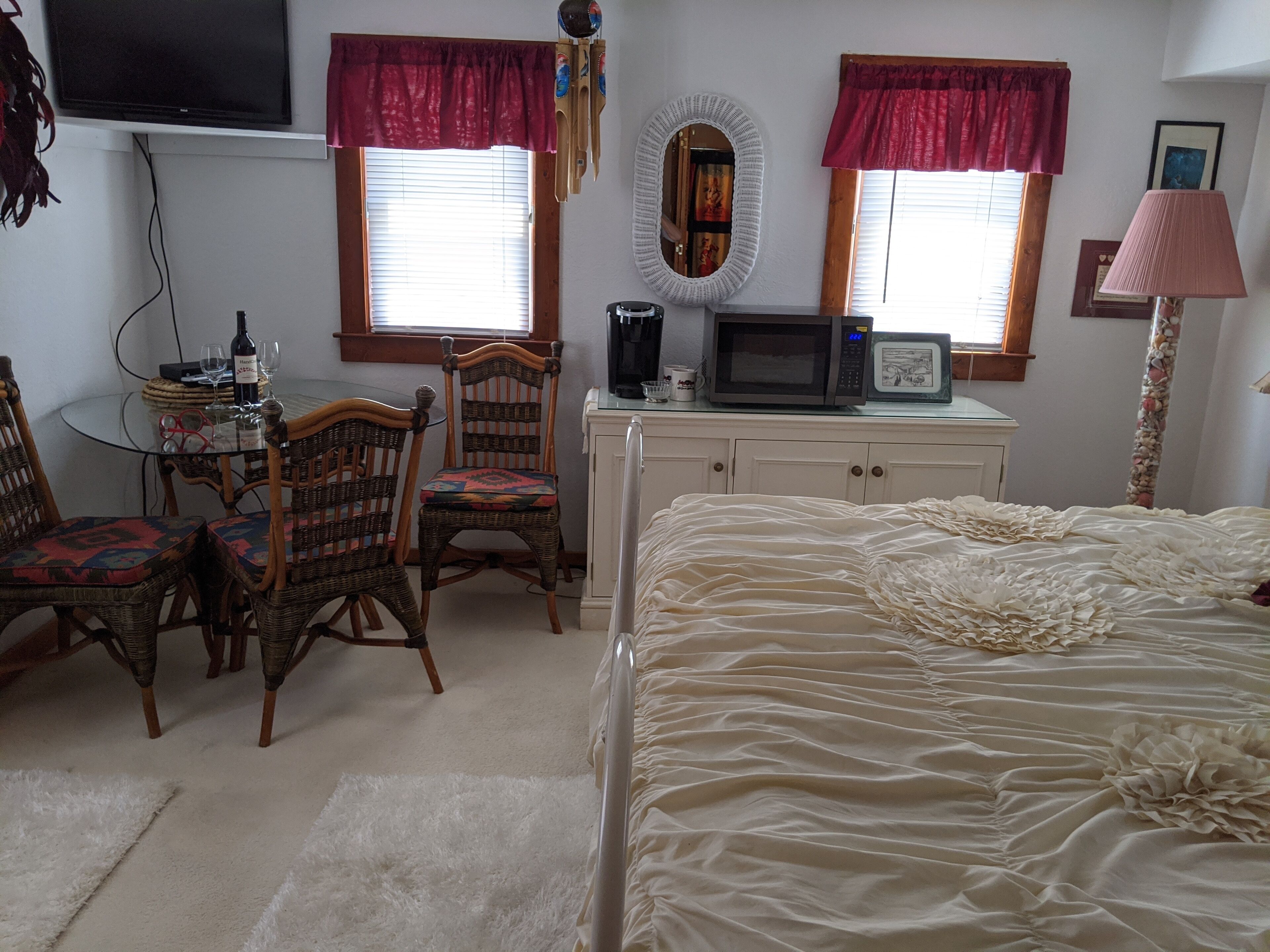 A bedroom with a bed, a desk with a computer, two chairs, a television, and a microwave.