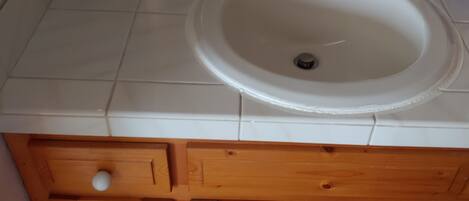 A bathroom with a white sink, wooden cabinets, and a red carpet.