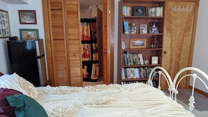 A bedroom with a large bed, a wardrobe, a bookshelf, and a door. - Beautiful Ocean Front Studio with direct beach and access to a deck.  (Kill Devil Hills)