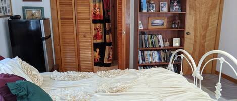 A bedroom with a large bed, a wardrobe, a bookshelf, and a door.
