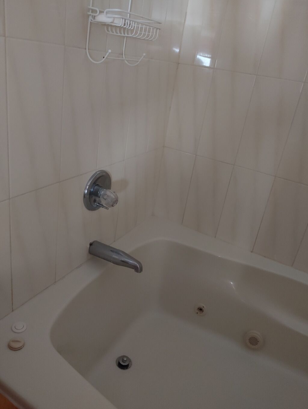 Een badkamer met een witte badkuip, een chromen kraan en een douchekop die aan de muur is bevestigd.